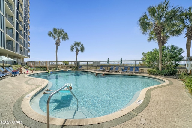 community pool with a patio area and fence