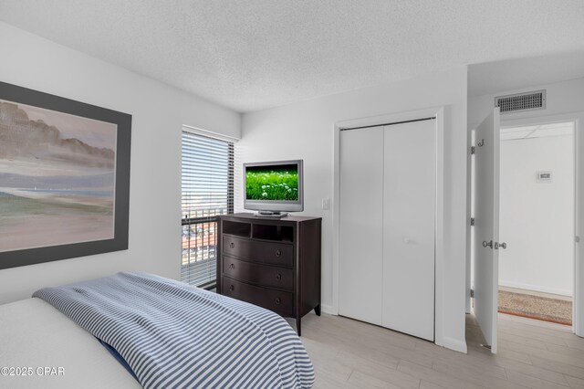 bedroom with a textured ceiling, light hardwood / wood-style floors, and a closet