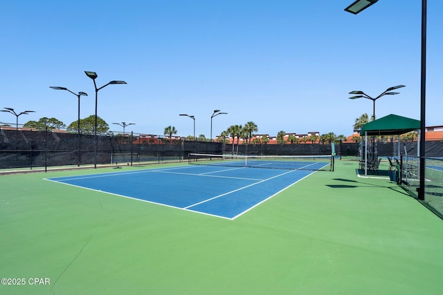 view of tennis court with community basketball court and fence