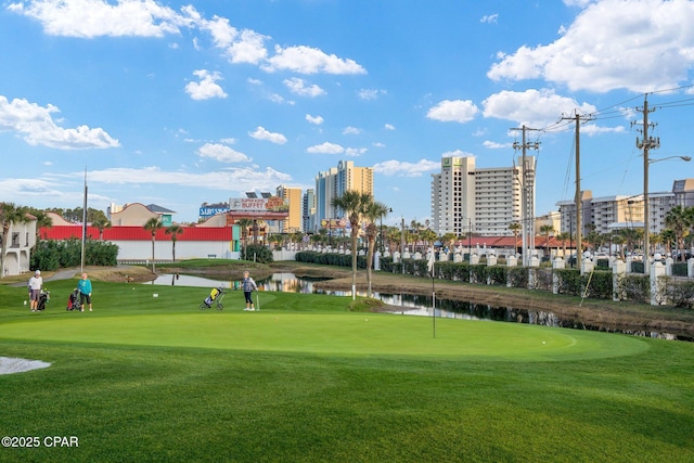 view of community with golf course view, a yard, and a water view