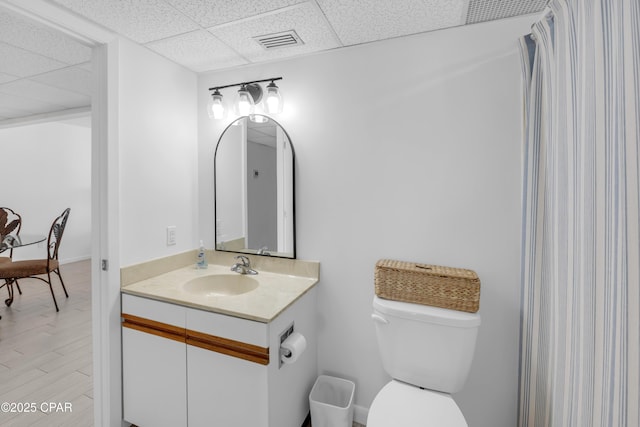 bathroom with vanity, hardwood / wood-style flooring, a paneled ceiling, and toilet