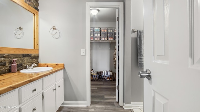 bathroom with baseboards, vanity, decorative backsplash, and wood finished floors