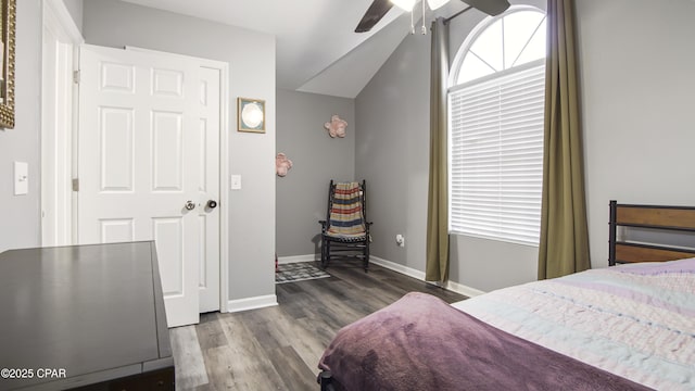 bedroom with multiple windows, vaulted ceiling, baseboards, and wood finished floors