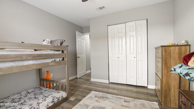 bedroom with baseboards, visible vents, a ceiling fan, wood finished floors, and a closet