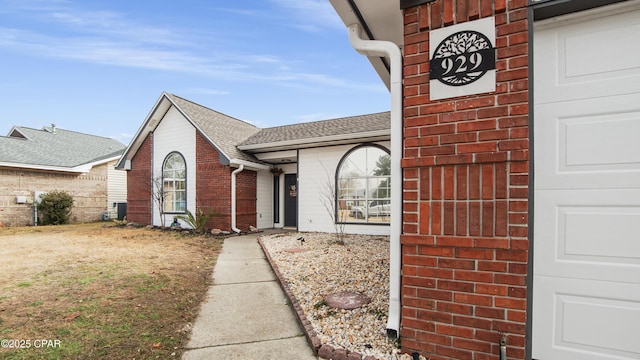 exterior space featuring a garage, a shingled roof, and brick siding