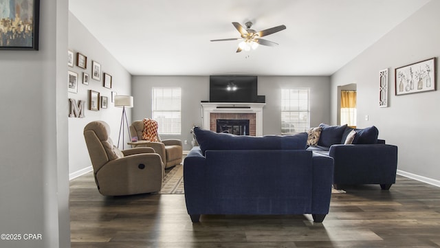 living room with ceiling fan, a fireplace, baseboards, and dark wood-style flooring