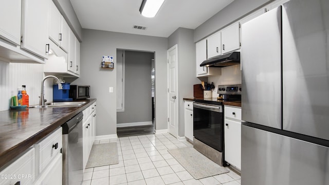 kitchen featuring visible vents, butcher block counters, appliances with stainless steel finishes, under cabinet range hood, and a sink