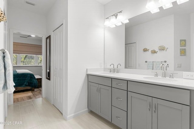 bathroom with double vanity, baseboards, visible vents, and a sink