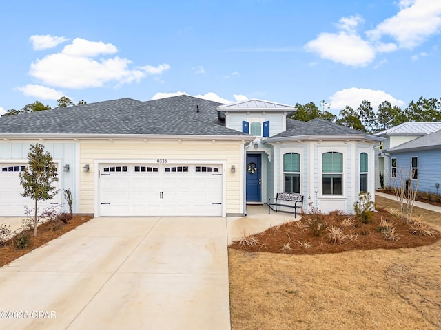 view of front of property with board and batten siding, concrete driveway, a garage, and roof with shingles