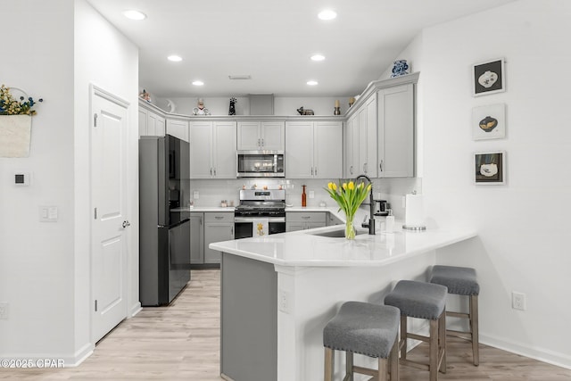 kitchen with tasteful backsplash, a kitchen bar, appliances with stainless steel finishes, a peninsula, and a sink