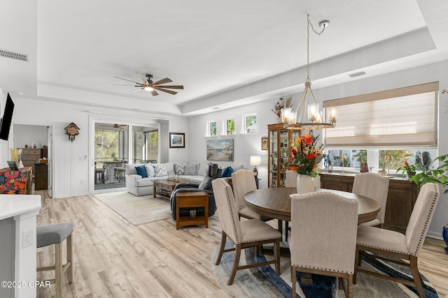 dining space featuring a tray ceiling, plenty of natural light, and visible vents