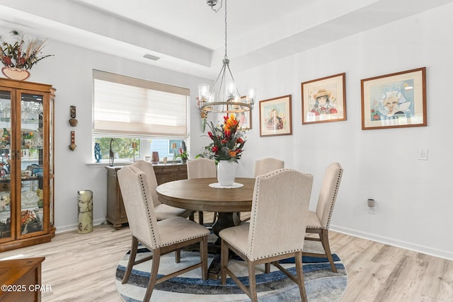 dining room featuring visible vents, baseboards, a notable chandelier, and light wood finished floors