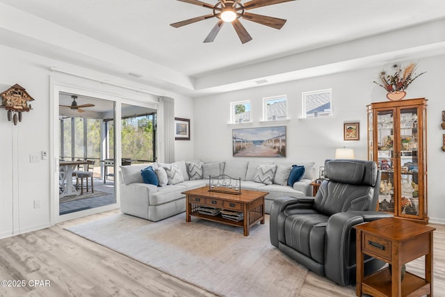 living area featuring visible vents, baseboards, ceiling fan, and light wood finished floors