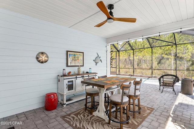 view of patio featuring outdoor dining area, glass enclosure, and a ceiling fan