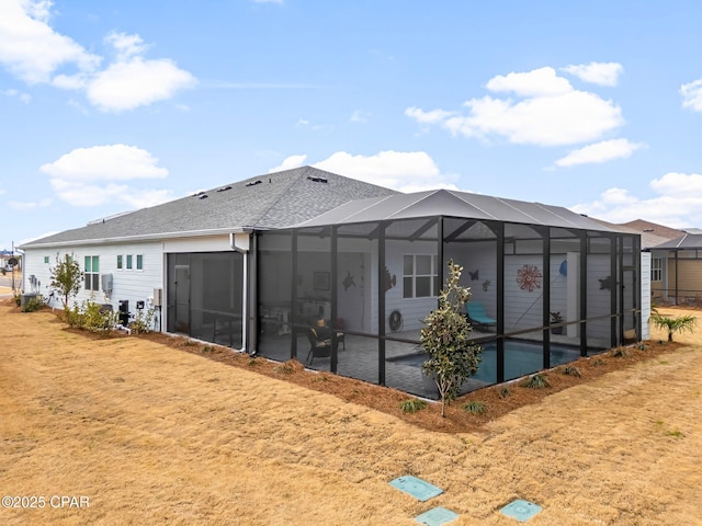 back of house featuring glass enclosure, a shingled roof, and a patio