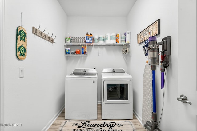 washroom featuring laundry area, light wood-style floors, baseboards, and washer and clothes dryer