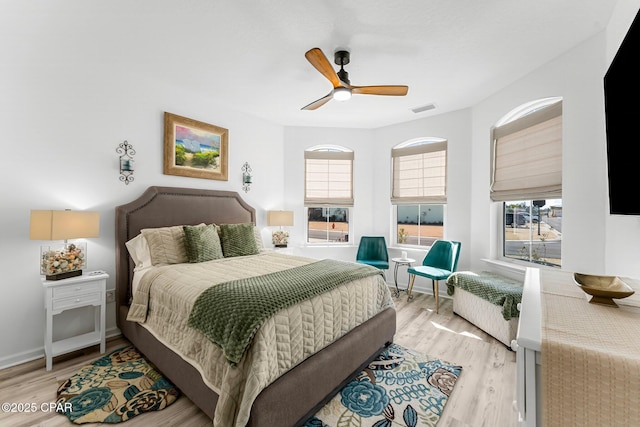 bedroom featuring visible vents, multiple windows, light wood-type flooring, and a ceiling fan