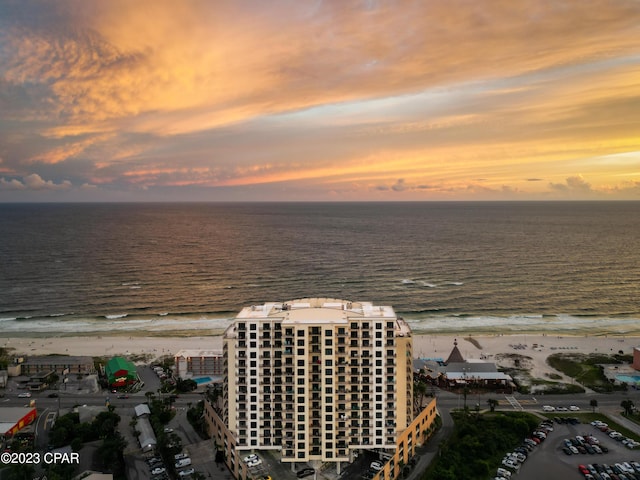 aerial view at dusk with a view of the beach and a water view