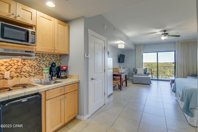 kitchen with cooktop, sink, tile countertops, light brown cabinets, and decorative backsplash