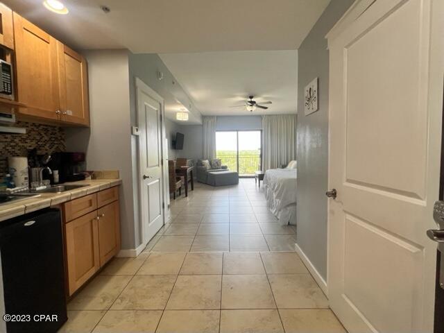 kitchen featuring sink, black dishwasher, tasteful backsplash, tile counters, and light tile patterned flooring