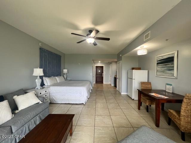 bedroom with white fridge, light tile patterned floors, and ceiling fan