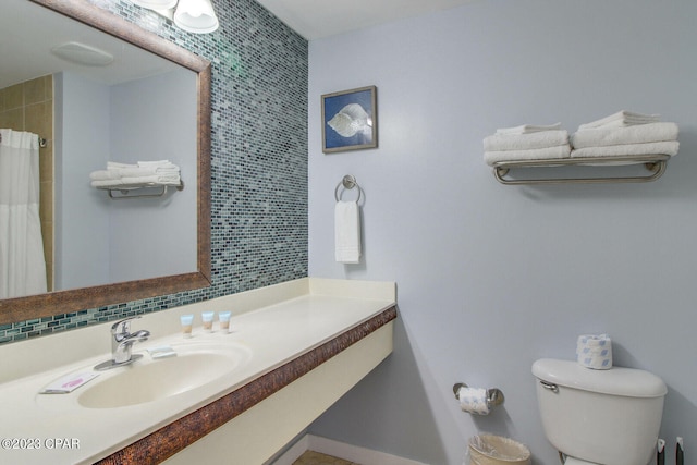 bathroom with tasteful backsplash, walk in shower, sink, and toilet