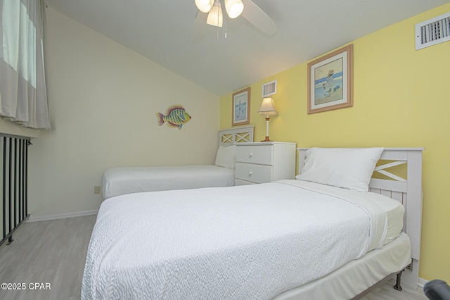 bedroom featuring lofted ceiling, radiator, light hardwood / wood-style flooring, and ceiling fan