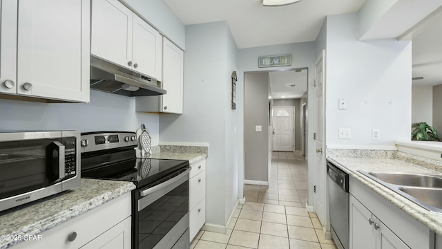 kitchen featuring appliances with stainless steel finishes, sink, white cabinets, light tile patterned floors, and light stone countertops