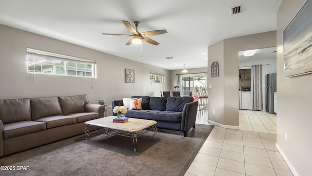 tiled living room with washer / dryer and ceiling fan