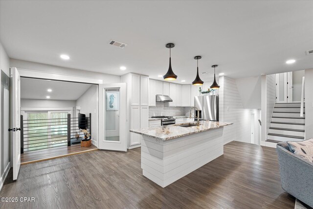 kitchen featuring appliances with stainless steel finishes, decorative light fixtures, white cabinetry, sink, and light stone countertops