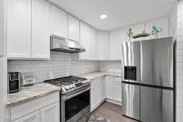 kitchen featuring tasteful backsplash, light stone countertops, white cabinets, and appliances with stainless steel finishes