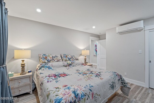 bedroom with a wall mounted AC and light hardwood / wood-style floors