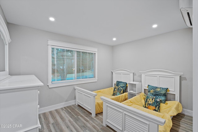 bedroom with light hardwood / wood-style floors and a wall mounted AC