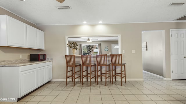 kitchen featuring white cabinetry, a textured ceiling, and ceiling fan