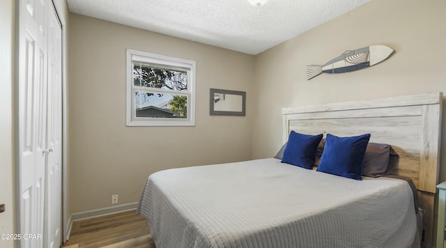 bedroom with a textured ceiling, light wood-type flooring, and a closet