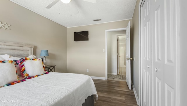 bedroom featuring dark hardwood / wood-style flooring, ceiling fan, a closet, and a textured ceiling