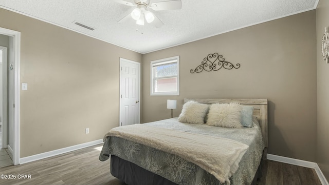 bedroom featuring ceiling fan, wood-type flooring, ornamental molding, and a textured ceiling