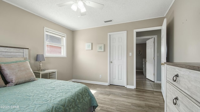 bedroom featuring ceiling fan, wood-type flooring, ornamental molding, and a textured ceiling