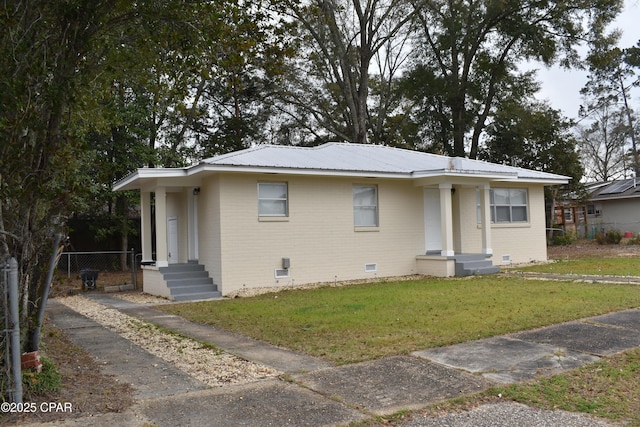 bungalow with a front yard, metal roof, crawl space, fence, and brick siding