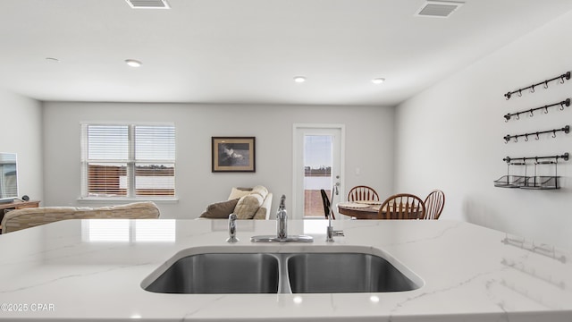 kitchen featuring light stone counters and sink