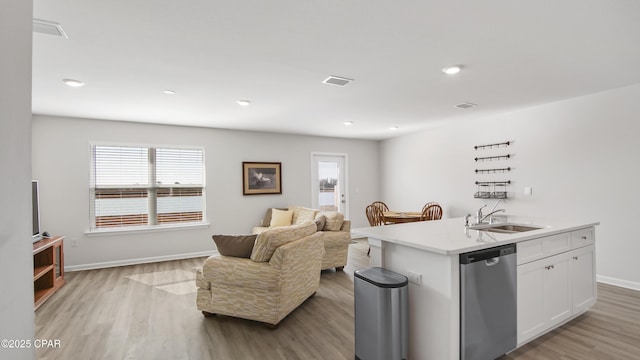 kitchen with sink, a center island with sink, light wood-type flooring, stainless steel dishwasher, and white cabinets