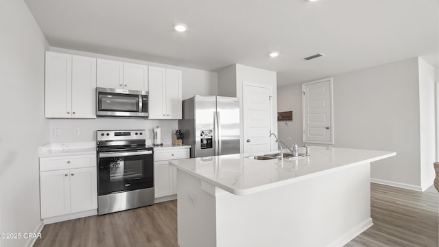 kitchen with sink, appliances with stainless steel finishes, dark hardwood / wood-style flooring, a kitchen island with sink, and white cabinets