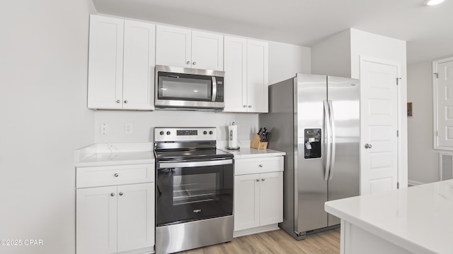 kitchen featuring appliances with stainless steel finishes, white cabinets, and light wood-type flooring