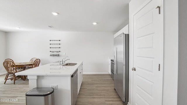 kitchen featuring sink, white cabinets, a kitchen island with sink, stainless steel appliances, and light hardwood / wood-style flooring