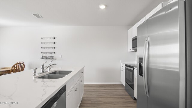 kitchen featuring white cabinetry, sink, dark hardwood / wood-style flooring, stainless steel appliances, and light stone countertops