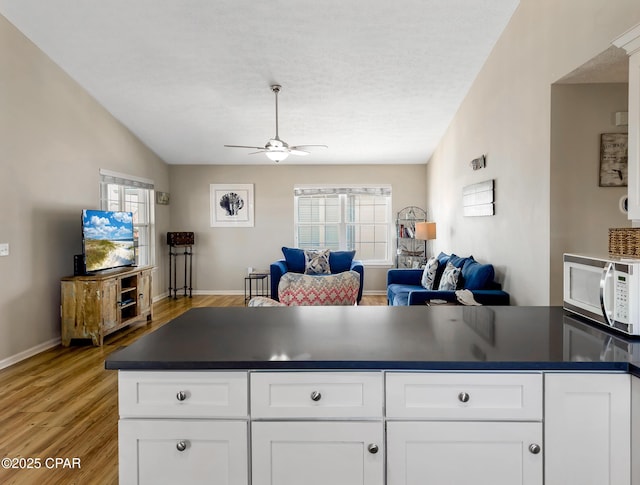 kitchen featuring a wealth of natural light, white cabinets, and light hardwood / wood-style floors