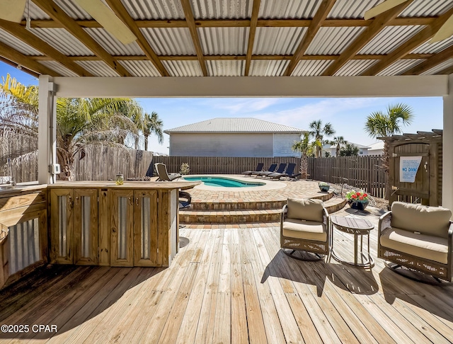 wooden deck featuring a bar and a fenced in pool