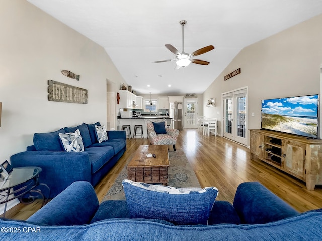 living room with ceiling fan, high vaulted ceiling, light wood-type flooring, and french doors