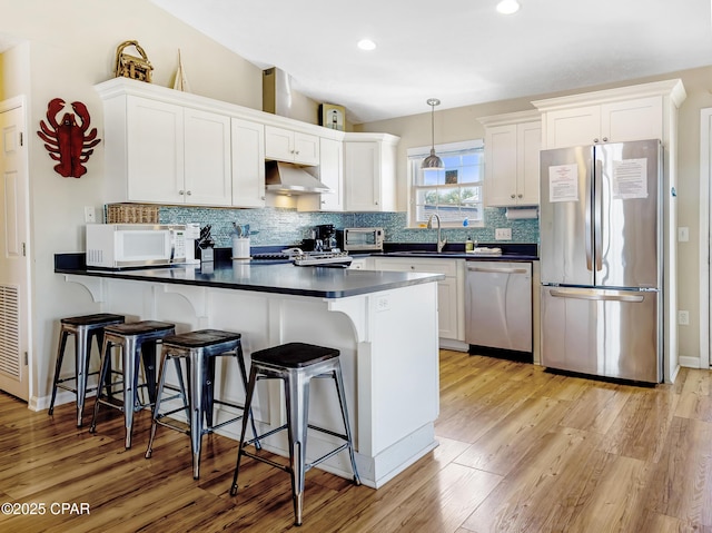 kitchen with tasteful backsplash, hanging light fixtures, stainless steel appliances, and white cabinets