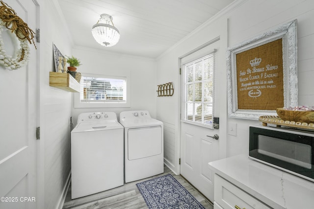 laundry room featuring ornamental molding, washing machine and clothes dryer, and light hardwood / wood-style floors